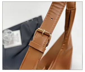 Detail of brown leather tote showing adjustable strap with gold buckle and stitching