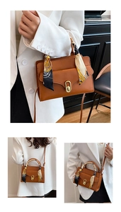 Detail of brown faux leather handbag with silk scarf handle and gold rotary lock