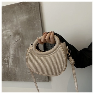 Detail of gold semicircular handbag featuring vertical embossed glitter texture and round handle