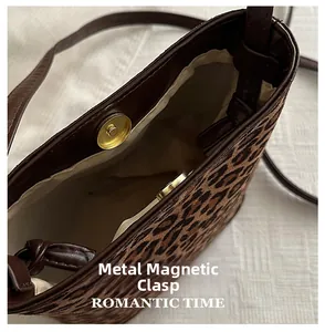 Detail of hardware magnetic snap closure on leopard print crossbody bucket bag