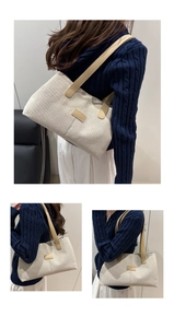 Detail view of a beige canvas tote bag featuring brown leather straps and a minimalist label