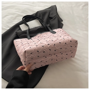 Detail of pink floral tote bag with black bow patterns and leather straps on blazer