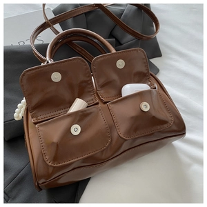 Detail view of dark brown leather Boston bag with pearl strap and interior storage space