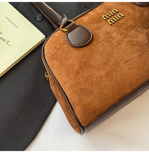 Detail der braunen Wildledertasche mit Goldlogo und glattem Lederbesatz im Vintage-Stil