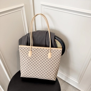 Large vintage monogram tote bag with tan leather straps on a modern chair