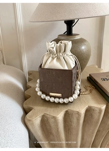 Detail of retro color-block bucket bag with elegant pearl handle and drawstring closure