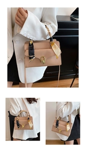Detail of beige envelope handbag with silk scarf handle and golden oval twist lock