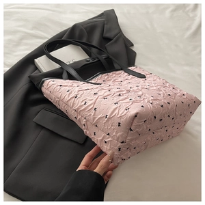 Detail of pink pleated tote bag with black bow print and reinforced handle stitching