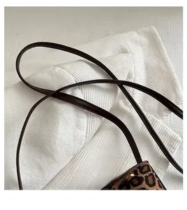 Detail of leopard print handbag showing dark brown leather handle and woven texture