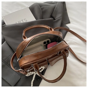 Macro view of interior storage in a shiny caramel Boston bag with pearl chain detail