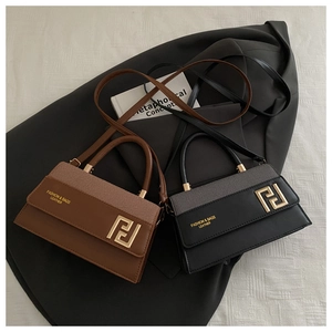 Detail view of textured leather crossbody bags with gold geometric hardware in brown and black