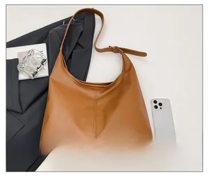 Top view of large brown faux leather hobo bag with adjustable strap on minimalist background