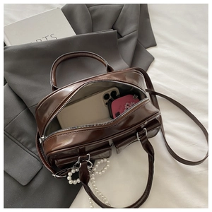 Top view of deep brown glossy Boston bag showing large interior capacity with phone and pouch
