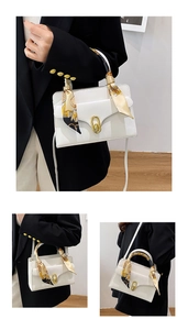 Detail of white leather mini bag with silk scarf handle and gold oval metal lock