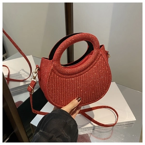 Close-up of red sequined half-moon bag with wavy texture and gold ring handle