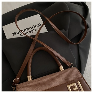 Close-up of vintage brown shoulder bag featuring woven fabric and gold buckle detail