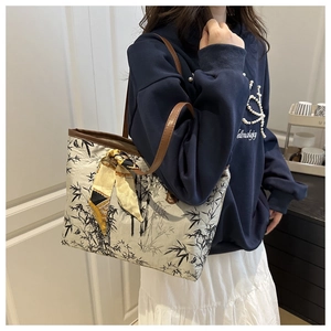 Detail of embroidered bamboo patterns and printed silk scarf on a stylish canvas tote bag