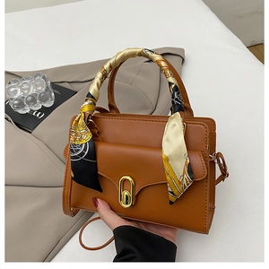 Détail d'un sac marron avec poignée en foulard de soie et fermoir rotatif doré élégant