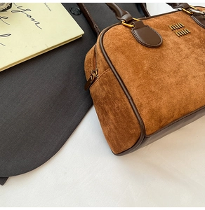 Nahaufnahme der braunen Wildleder-Boston-Tasche mit Retro-Logo und Lederverzierung