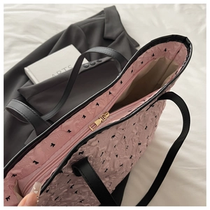 Detail of pink jacquard tote bag with bow patterns, leather straps and gold zipper