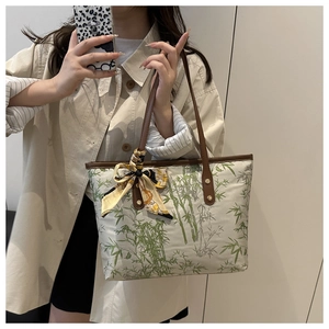 Detail of bamboo print tote bag with brown leather straps and decorative silk scarf