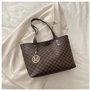 Détail du cabas marron avec motif monogramme M et breloque en métal doré lettre M