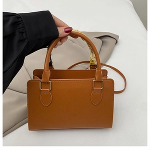Close-up of brown faux leather handbag with colorful silk scarf wrapped on the handle