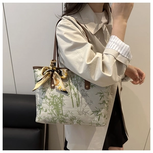 Close-up of canvas tote bag with bamboo print and decorative yellow silk scarf