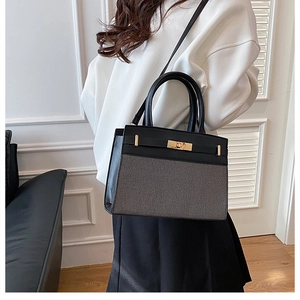 Détail du sac à main élégant en cuir noir et tissu gris avec fermoir doré rotatif
