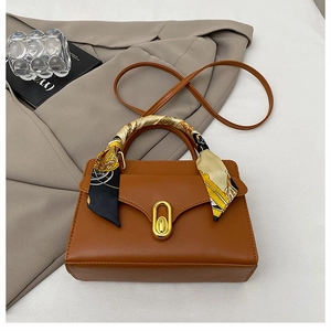 Détail d'un sac à main en cuir marron avec foulard en soie et boucle dorée