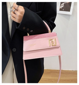 Détail d'un sac à main en cuir rose avec logo en métal doré et bandoulière réglable