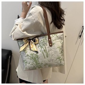 Détail d'un sac cabas en toile blanche avec motifs de bambou vert et anses en cuir