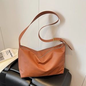 Minimalist caramel brown leather tote bag with adjustable strap and gold hardware