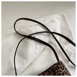 Detailed view of plush leopard print texture and dark brown leather strap on shoulder bag