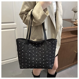 Detail of black tote bag with white bow pattern and 3D pleated texture on leather
