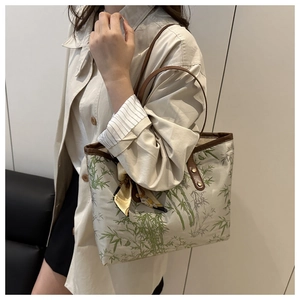 Detail of canvas tote bag with green bamboo print, leather handles and silk scarf