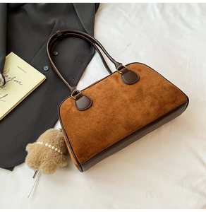 Detail der Vintage-Wildledertasche mit Plüschstern und Perle auf weißem Stoffhintergrund