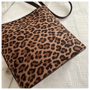 Close-up of leopard print shoulder bag with plush texture and brown leather strap