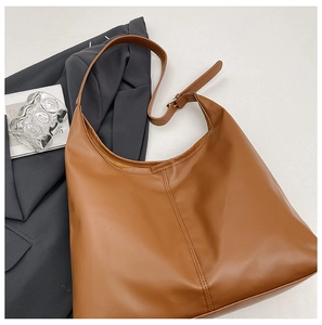 Macro view of brown leather tote bag showing high-quality vertical double stitching detail