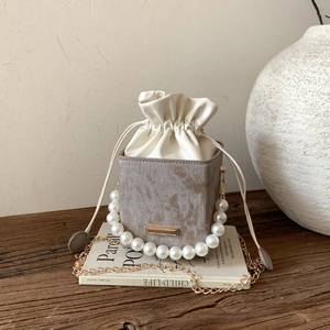 Luxe marble texture bucket bag with pearl handle and gold chain strap on vintage book