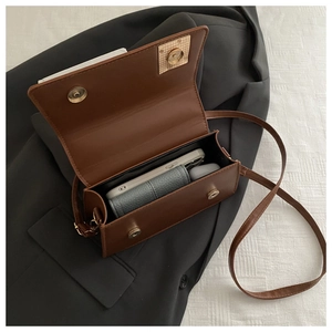 Internal view of brown leather crossbody bag holding a phone, wallet, and earphone case