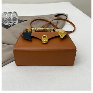 Sac à main marron en cuir avec foulard en soie et fermoir doré sur blazer beige