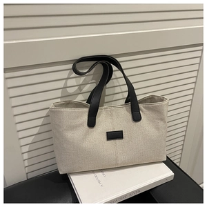 Close-up of minimalist linen tote bag with contrast leather handles and logo patch
