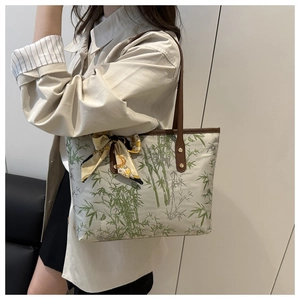Detail of bamboo print canvas tote bag with brown leather handles and decorative silk scarf
