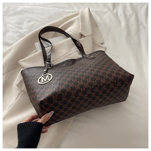Détail du sac cabas marron avec imprimé monogramme, poignées fines et breloque en M