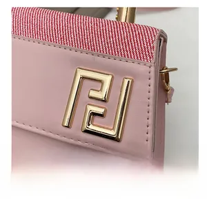 Détail du sac en cuir rose avec tissu à rayures rouges et logo en métal doré