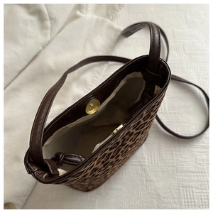 Detail view of leopard print bucket bag featuring gold magnetic closure and interior lining