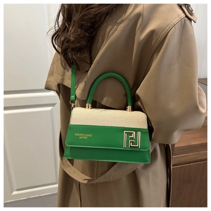 Detail of two-tone green leather and cream fabric handbag with gold geometric buckle