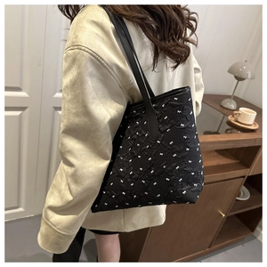 Detail of black tote bag featuring white bow embroidery and pleated bubble texture fabric