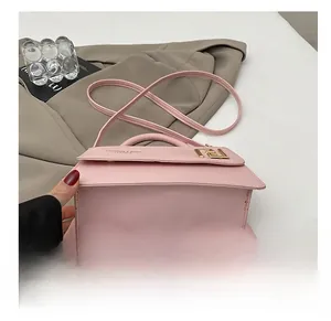 Vue détaillée du sac à main rose en similicuir avec logo doré et base plate durable